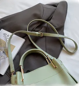 Detailed view of adjustable long strap and gold metal hardware on sage green bucket bag