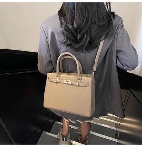 Detailed view of beige handbag showing the classic turn-lock and handle design