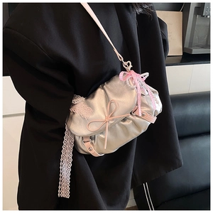 Détail du sac bandoulière argenté métallisé avec nœuds roses et bordure en dentelle