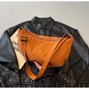 Detail of orange crescent crossbody bag showing nylon texture and adjustable strap buckle