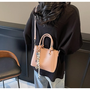 Vue détaillée du sac seau en cuir rose avec foulard en soie et pendentifs métalliques