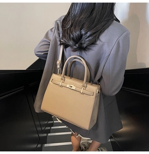 Beige leather handbag with metal lock shown in a lifestyle street style scene