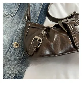 Detail shot of vintage brown faux leather shoulder bag with metallic buckle and rivets