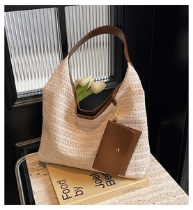 Close-up of woven straw tote bag with brown leather strap and small hanging wallet