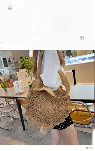 Detail of hand-woven straw bag featuring decorative scalloped edges and wide strap