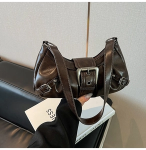 Detail of vintage brown leather shoulder bag with glossy distressed finish and metal buckle