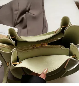 Detail of the sage green handbag showing smooth gold zipper closure and interior layout