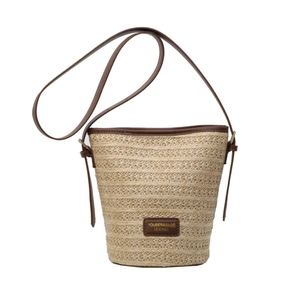 Straw bucket bag with dark brown leather trim and shoulder strap for summer beach style