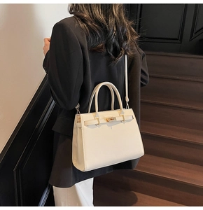 Back view of model wearing a medium cream leather tote bag with gold metal hardware