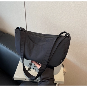 Close-up of black nylon crescent bag with wide strap and side fashion label
