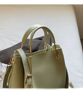 Detail of sage green bucket bag with golden circular handle and adjustable shoulder strap