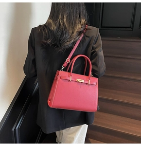 Deep red leather handbag for women featuring gold hardware shown on person with black blazer