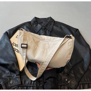 Detail view of the beige crescent crossbody bag with a focus on fabric and strap buckle