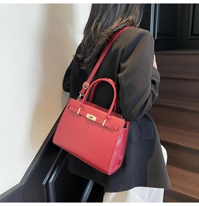 Detail of red leather handbag with gold metal clasp and adjustable shoulder strap