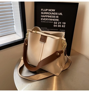 Detail of cream bucket bag with dark brown strap and premium gold metal hardware