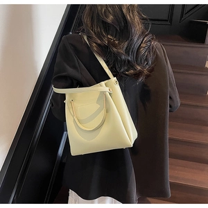 Detailed close-up of light green bucket bag with gold metal handle and leather strap