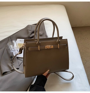 Detail view of khaki leather tote bag with gold lock and strap on office decor