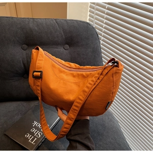 Detailed texture of orange nylon crescent bag with adjustable strap and fashion label