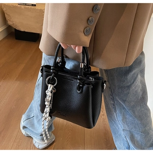 Détail du sac seau noir en cuir grainé avec anneaux argentés et breloque en corde