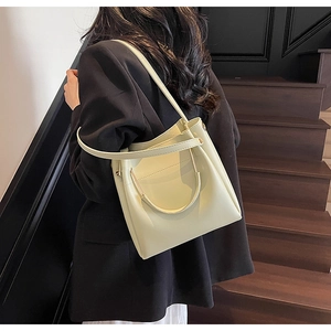 Detail of minimalist bucket bag with metallic handles and leather texture in a lifestyle setting
