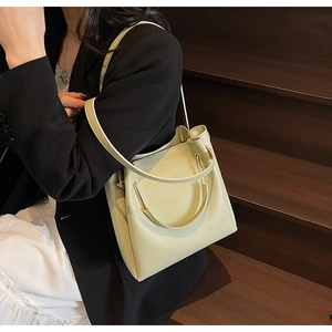 Detail view of light green leather bucket bag with metal ring handle on model