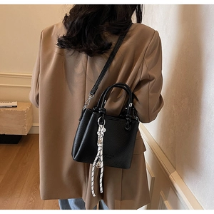 Détail d'un sac seau en cuir noir grainé avec accessoire en corde tressée