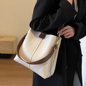 Fashionable beige bucket bag with wide brown strap and metallic gold hardware detail
