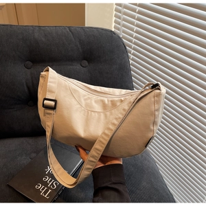 Detail of minimalist beige nylon crescent bag featuring adjustable strap and smooth texture