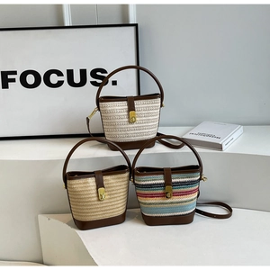 Close-up of contrast woven straw bucket bags with leather handles and gold metal locks