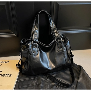 Detail of glossy black PU leather tote bag with silver rivets and metal adjustment buckle