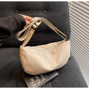 Detail of adjustable strap and fashion label on beige nylon crescent crossbody bag