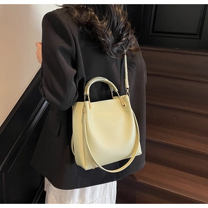 Pistachio green bucket bag worn over the shoulder with adjustable strap and gold hardware