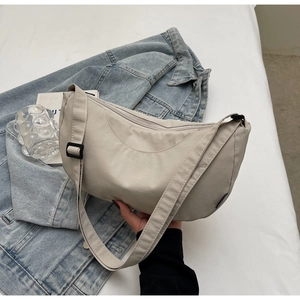 Detail view of cream crescent crossbody bag with adjustable strap and textured fabric