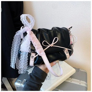 Détail du sac froncé noir avec bandoulière en cuir rose et noeud en dentelle blanche