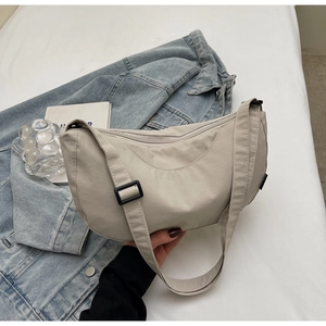 Detail of off-white crescent crossbody bag with adjustable wide strap and side label
