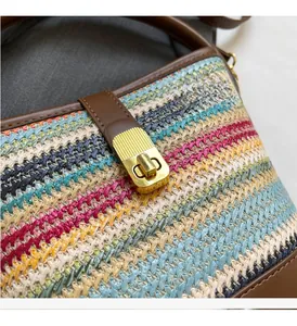 Detail of multi-color woven handbag featuring premium gold metal twist lock and leather trim