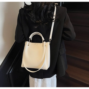 Detail of cream bucket bag with gold ring handle worn by model on stairs