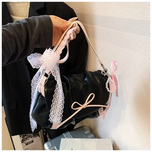 Détail du sac plissé noir avec nœud rose, ruban en dentelle et breloque cœur perle
