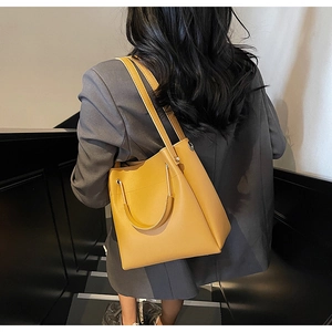 Detail view of ginger yellow leather bucket bag with semi-circular metal top handle