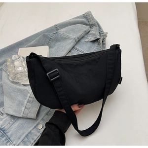 Detail of black nylon half-moon crossbody bag with adjustable strap and fashion label