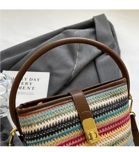 Detail of multi-color woven bucket bag with brown leather strap and gold metallic buckle