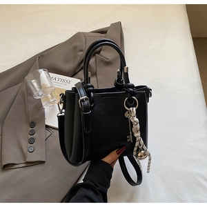 Détail du sac seau en cuir noir grainé avec ferrures argentées et porte-clés tressé
