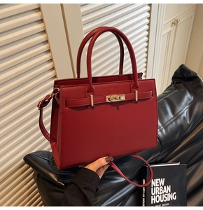 Detail view of burgundy leather handbag with gold twist lock and dual top handles