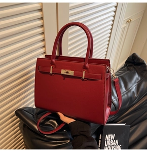 Detail of burgundy cross-grain leather handbag with gold metal lock and shoulder strap