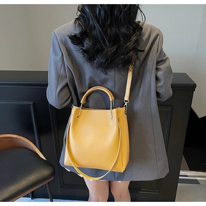 Chic yellow bucket bag shown on a grey blazer for daily commuting style and scale