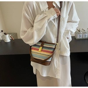 Detail of multi-color woven crossbody bag with brown leather accents and gold buckle
