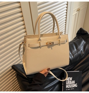 Detail of cream leather tote bag with gold lock hardware and textured grain finish