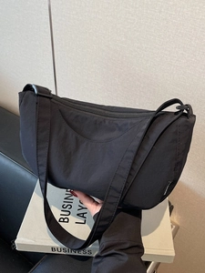 Minimalist black nylon crescent moon bag with wide strap for casual daily commuting style