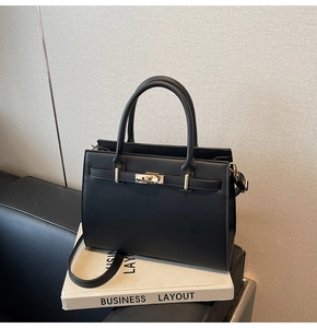 Detail of black Saffiano leather briefcase style handbag with gold hardware and top handle