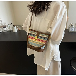 Detail of multi-color woven bucket bag with brown faux leather strap and golden metal lock